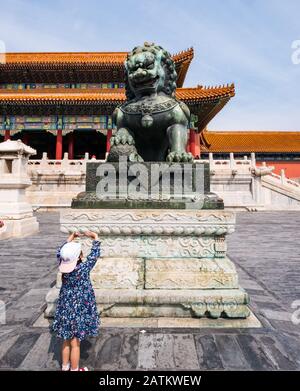 Junges Kind, das auf den bronzenen Schutzlöwen blickt, Tor der Obersten Harmonie, Äußerer Gerichtshof, Verbotene Stadt, Peking, China Stockfoto