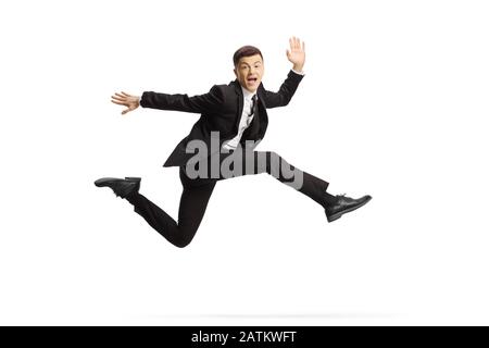 Fröhlicher junger Mann in einem schwarzen Anzug springt und betrachtet die Kamera isoliert auf weißem Hintergrund Stockfoto