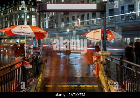 Oxford Circus Station während der Hauptverkehrszeit in der Nacht. Foto mit langer Belichtung, das die Bewegung von Menschen und Verkehr zeigt. Stockfoto