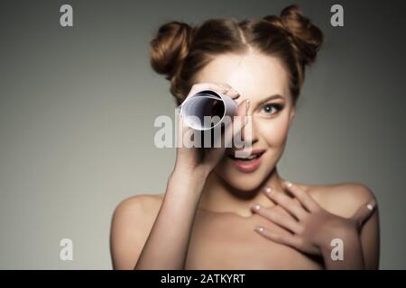 Schönes Mädchen sieht in einem Teleskop in der Papierrolle aus. Nachrichten und Klatsch im Pfadfindertum. Stockfoto