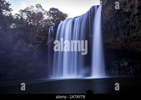 Blick auf Rainbow fällt mit einer Höhle unter einer Klippe hinter den Stürzen in Kerikeri nach Sonnenuntergang, Neuseeland, Northland Stockfoto