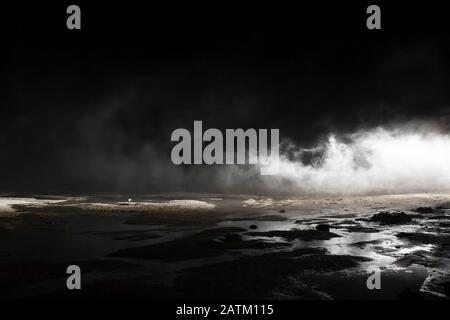 Abstrakter mars wie Gelände, schlammige Pfütze mit Wassertexturen, Felsen, starker Nebel Stockfoto