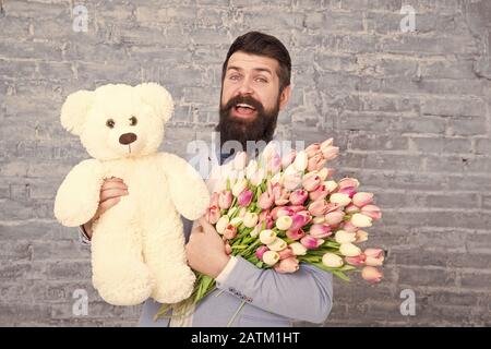 Warten auf Darling. Mann gut gepflegt Verschleiß tuxedo Bow Tie halten Blumen Tulpen Bouquet und großen Teddybären Spielzeug. Laden Sie dating. Romantisches Geschenk. Romantischen Mann. Macho fertig, romantisches Date. Stockfoto