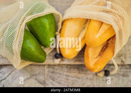 Frisches Brot, Avocado und Tomaten in einer wiederverwendbaren Tasche auf einer stilvollen Holzküche. Null-Abfall-Konzept Stockfoto