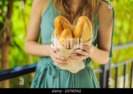 Wiederverwendbare Lebensmittellaschen mit Brot in den Händen einer jungen Frau. Keine Abfallbeseitigung. Null-Abfall-Konzept Stockfoto