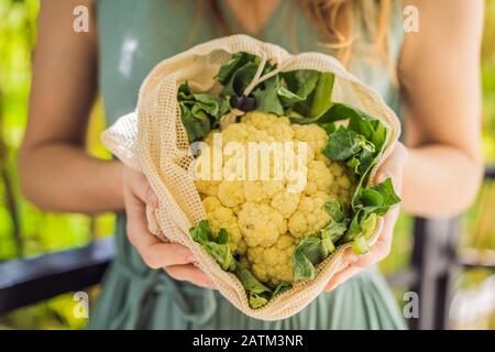 Blumenkohl in einem wiederverwendbaren Beutel in den Händen einer jungen Frau. Null-Abfall-Konzept Stockfoto