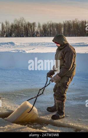 Der Monteur mit Stahlzange zieht den Eisblock heraus Stockfoto