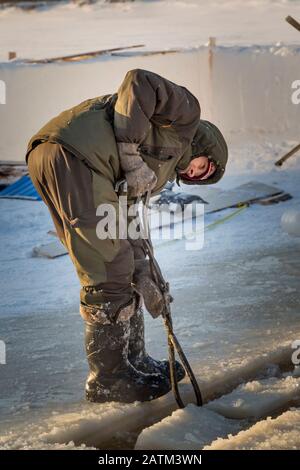 Der Monteur mit Stahlzange zieht den Eisblock heraus Stockfoto