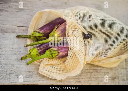 Auberginen in einer wiederverwendbaren Tasche auf einer stilvollen Holzküche. Null-Abfall-Konzept Stockfoto