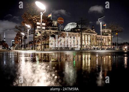 Berlin, Deutschland. Februar 2020. Das Gebäude des Reichstags spiegelt sich in der feuchten Straße wider. Credit: Britta Pedersen / dpa-Zentralbild / dpa / Alamy Live News Stockfoto