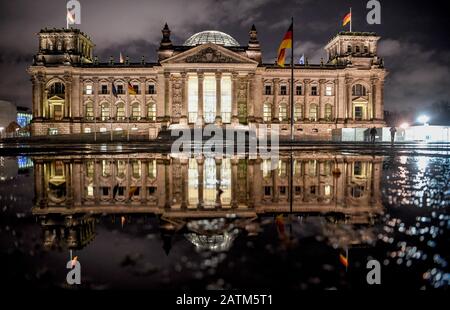 Berlin, Deutschland. Februar 2020. Das Gebäude des Reichstags spiegelt sich in einer Pfütze wider. Credit: Britta Pedersen / dpa-Zentralbild / dpa / Alamy Live News Stockfoto