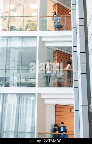 Moderne junge multiethnische Mitarbeiter des Business Centers arbeiten auf verschiedenen Etagen miteinander Stockfoto