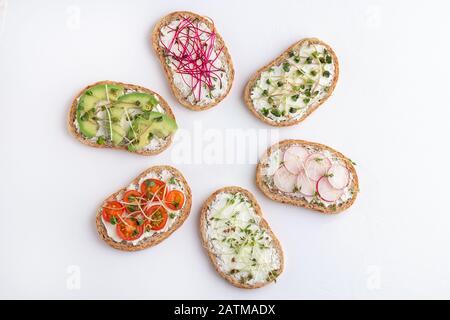 Verschiedene Sandwiches mit Mikrogrüns und Gemüse auf weißem Hintergrund. Ansicht von oben Stockfoto