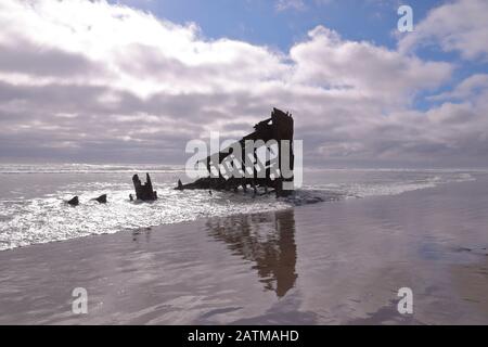 Schiffswrack an einem Strand. Blick auf Überreste von Peter Iredale - einem viermastigen Segelschiff aus Stahlbark an einem Ufer in der Nähe von Astoria, Oregon. Nasse Strandoberfläche Stockfoto