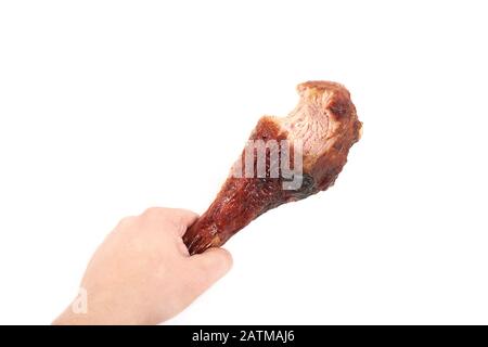 Hand mit gebratener Truthahn Bein mit Biss, auf weißem Hintergrund. Stockfoto
