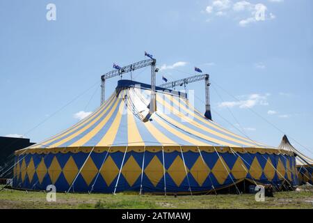 Blaues und gelbes Zirkuszelt mit australischen Flaggen oben. Stockfoto