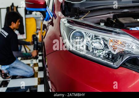 Man-Hände, die das Arbeitsgerät halten, polieren das Auto.Focus-Scheinwerfer. Autodetails. Stockfoto