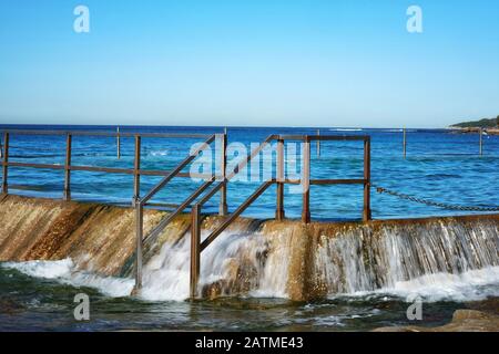 North Cronulla Rockpool, der von den eintreffenden Wellen und der Brandung überströmt wird, einer von vielen Ozeanpools, die die Küste von Sydney und seinen Hafen anführen. Stockfoto