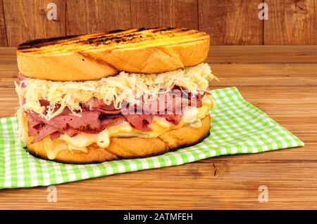 Sandwich im Pastrami-Reuben-Stil mit Sauerkraut und Schweizer Käse auf Holzgrund Stockfoto