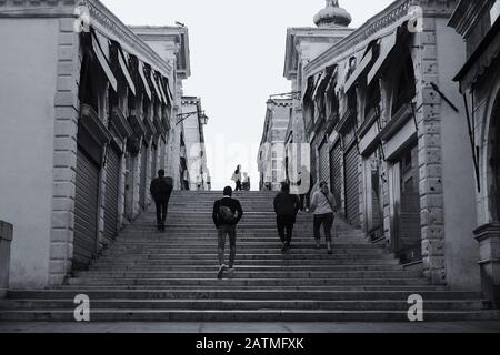 Auf der Rialto-Brücke am frühen Morgen gehen die Menschen die Treppe hinauf, bevor der Hektik des Tages in Venedig beginnt Stockfoto