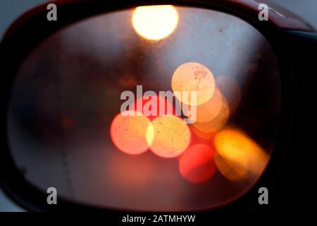 Stadtverkehr nachts, abstrakte verschwommene Kreise im Rückspiegel Stockfoto