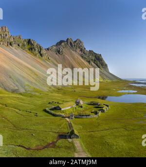 Isländische Luftlandschaften mit einem wikingerdorf in Stokksnes. Panorama auf den Vestrahorn-Berg an einem sonnigen Tag. Stockfoto