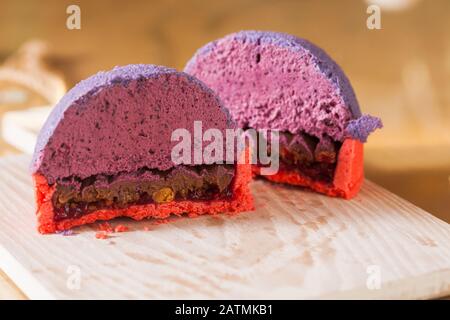 Geschnitten auf halbfranzösischem Mini-Mousse-Gebäck Dessert, Closeup. Moderner europäischer Portionskuchen mit Blaubeere Mousse Stockfoto