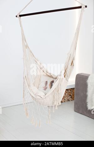 Moderne Hängematte im Wohnzimmer. Stilvolles Schlafzimmer mit natürlicher Saitenhängematte. Apartmentdesign im Loft- und Landhausstil. Platz zum Entspannen Stockfoto