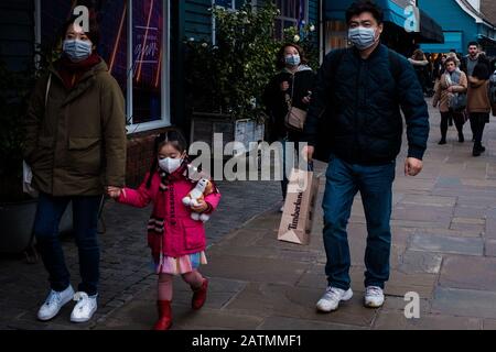 Eine asiatische Familie, die während des Einkaufs im Bicester Village in Oxfordshire während des Coronavirus Scare im Jahr 2020 Facemasks trägt Stockfoto