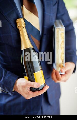 Mann mit Schachtel Pralinen und einer Flasche Wein Stockfoto