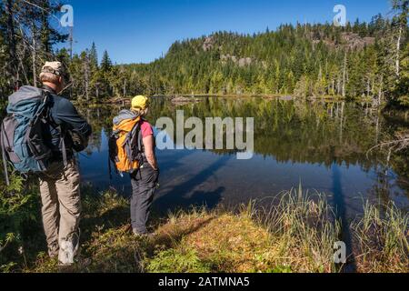 Ältere Wanderer am Little Nugedzi Lake im gemäßigten Regenwald, Quadra Island, British Columbia, Kanada Stockfoto