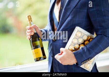 Mann mit Schachtel Pralinen und einer Flasche Wein Stockfoto