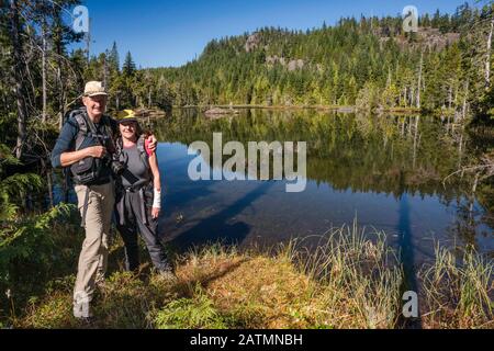 Ältere Wanderer am Little Nugedzi Lake im gemäßigten Regenwald, Quadra Island, British Columbia, Kanada Stockfoto