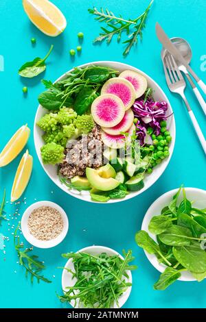 Vegane Mittagsschüssel mit Quinoa, Gurke, grünen Erbsen, Rettich, Romanesco und Rotkohl, Avocado, Spinat und Arugulasalat, gesundem Essen, vegetarisch Stockfoto