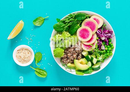 Vegane Mittagsschüssel mit Quinoa, Gurke, grünen Erbsen, Rettich, Romanesco und Rotkohl, Avocado, Spinat und Arugulasalat, gesundem Essen, vegetarisch Stockfoto