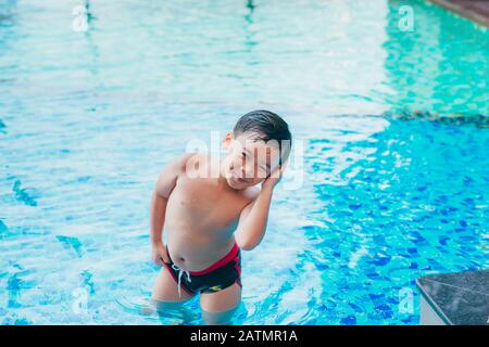 Cute asian kid Reinigung Ohren nach dem Schwimmen in einem Pool Stockfoto