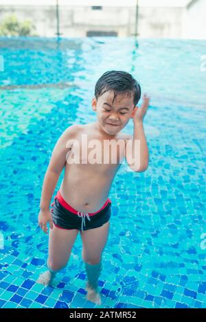 Cute asian kid Reinigung Ohren nach dem Schwimmen in einem Pool Stockfoto