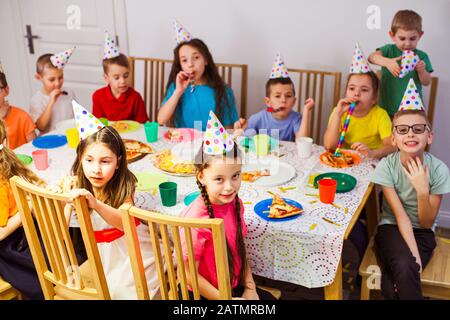 Feiernde Kinder feiern gemeinsam Geburtstag. Kinder, die Pizza essen und Party genießen Stockfoto