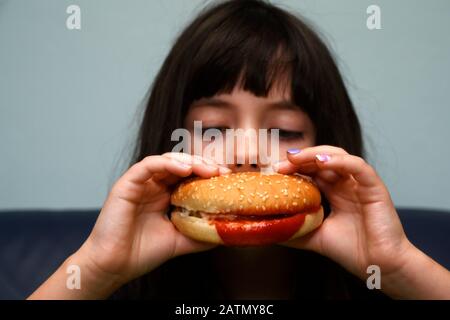 6-jähriges Mädchen, das einen Hühnerburger isst Stockfoto