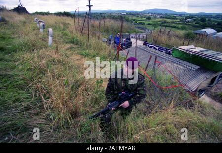 Die britische Armee bemannte einen der letzten Wachtürme namens Golf Zero One mit Blick auf den Verwaltungsbereich von South Armagh, Nordirland. Mitglieder des Fallschirmregiments sitzen in ihrem Stahlbehälter, der als Wohnfach dient, und sehen Videobänder und Fernsehen, während ihre Waffen in der Ecke weggestapelt sind. Diese Minibasis wurde wenige Tage später von der Mannschaft der Armeeingenieure als Teil des Rückzugs der British Army aus dem Gebiet entfernt. Stockfoto
