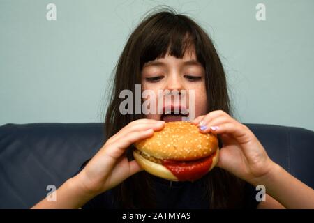 6-jähriges Mädchen, das einen Hühnerburger isst Stockfoto