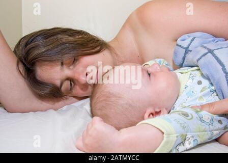 Baby Boy und Mutter Waking von schlafen kuschelte sich in Mamas Bett Stockfoto
