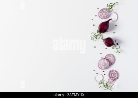 Kreative Komposition mit Scheiben roter Zwiebel, Gewürzen und Kräutern auf weißem Hintergrund Draufsicht. Flaches Lay. Kopierbereich. Stockfoto