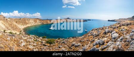 Boote, die in einer kleinen felsigen Bucht in der Nähe von Lindos verankert sind - Panorama (Rhodos, Griechenland) Stockfoto
