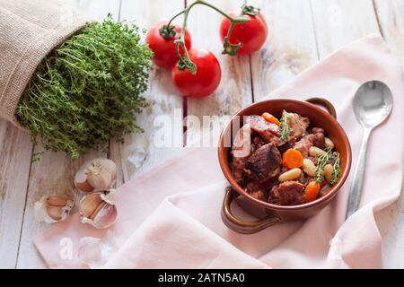 Cassoulet. Mit Fleisch Schweinefleischwürstchen, Gans, Ente und manchmal Hammel und zwei Arten von weißen Bohnen. Französische Küche. Auf altem weißen Holzhintergrund. Stockfoto