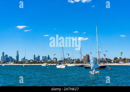 Melbourne, Australien - 7. Dezember 2016: Yachts, Segelboote und bunte Kitesurffallschirme mit Melbourner Stadtbild im Hintergrund Stockfoto