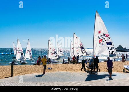 Melbourne, Australien - 7. Dezember 2016: Sportler, die Segelboote nach dem Wettkampf am St. Kilda-Strand pflegen Stockfoto