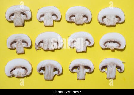 Champignon-Pilze-Scheiben auf gelbem Muster. Vegetarisches Essen Stockfoto