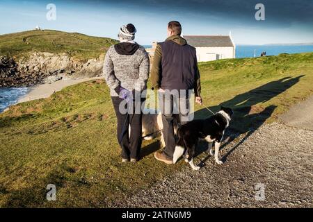 Menschen und ihre Hunde auf dem Küstenpfad, die auf dem Little Fistral in Newquay in Cornwall auf das Meer blicken. Stockfoto