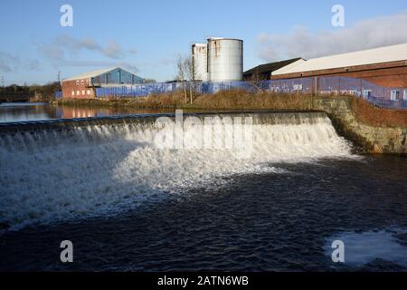 Wehr an der irwell mit Industriegebäuden und Silos in Der Hintergrund in radcliffe in Bury lancashire uk Stockfoto